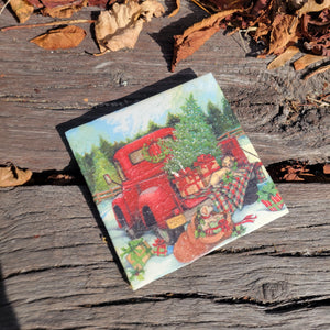 A hot plate with a painting of a snowy red truck carrying a golden dog, Christmas tree and presents