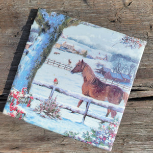 A hot plate with a painting of a horse behind a snowy fence.