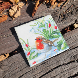 A hot plate with a painting of a red and brown bird in snowy grass.
