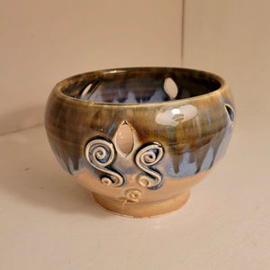 The side view of the small bowl focused on the cut out pattern that has two "s" shaped patterns below it.