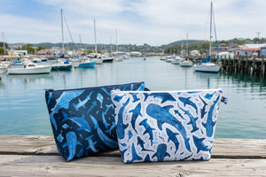 Two fabric pouches with shark patterns on a wooden surface