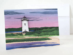 Paper cut depiction of Edgartown lighthouse with a sunset behind it
