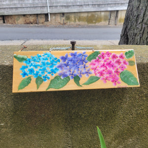 Blue, purple and pink painted flowers on a piece of cedar shingle