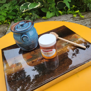 The cutting board decorated with a honey pot and a jar of honey