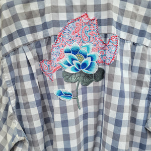 A gray plaid flannel with a multi colored island  shape and a blue flower