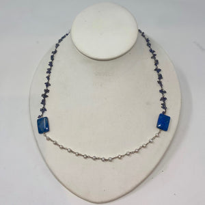 A blue crystal beads with two blue squared beads and a row of white small beads