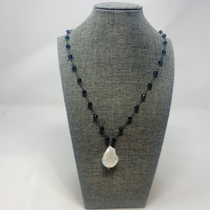 A blue beaded necklace with a large pearl