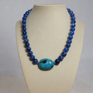 A blue beaded necklace with a turquoise centerpiece