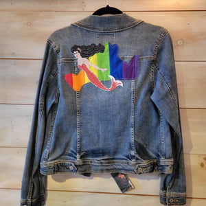 A denim jacket with a rainbow island and a mermaid with a red tail.