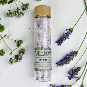 A vial filled with sea salt surrounded by dried lavender and small white flowers