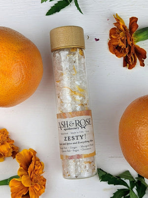 A vial filled with sea salt surrounded by lemons and dried flowers.