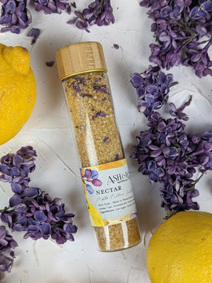 A vial filled with sea salt surrounded by dried small petals and lemons