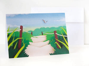 Paper cut depiction of a sandy walkway with a seagull flying above