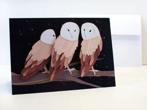 Paper cut depiction of three owls on a tree branch