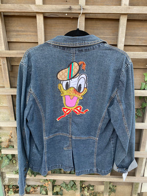 Dark blue denim jacket with a Donald the Duck cut out. He is wearing a "gucci" hat and a red bow tie.