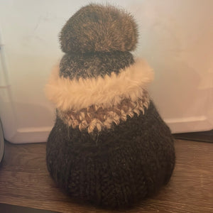 This is a brown and white hat with a tan pompom