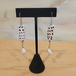 Gold wired earrings along with a rectange shaped cow print bead and Puka shells at the end.
