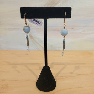 Gold wired earrings with a blue bead followed by a cylinder bead and smalled clear toned beads
