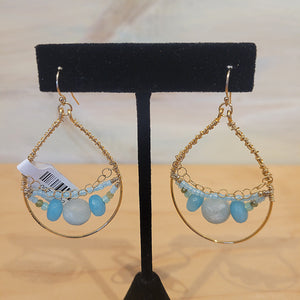 Gold hoop earrings with blue toned beads in the middle of the hoop.